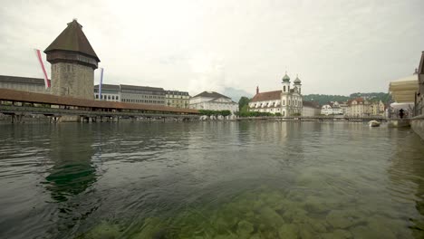 Low-angle-shot-of-flowing-river-Reuss,-Kapellbrücke-in-background