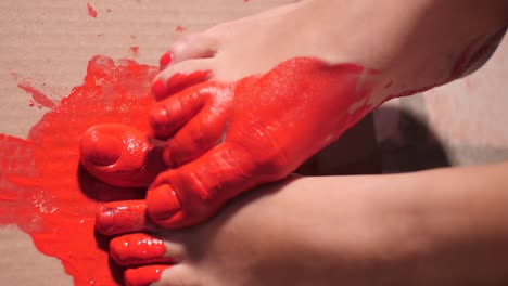 Nahaufnahme-Auf-Nackten-Füßen-Der-Performance-Künstlerin,-Die-Mit-Ihren-Füßen-Und-Roter-Farbe-Auf-Karton-Malt-|-Zeitlupe-Von-Schlammigen-Füßen-Mit-Acrylfarbe