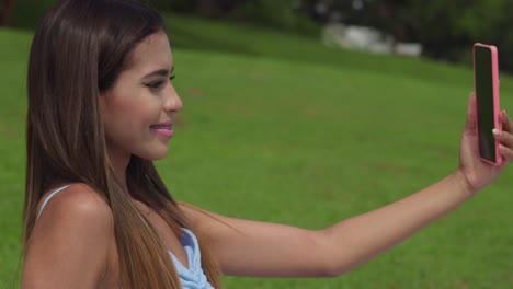 Junge-Hispanische-Frau,-Die-Ein-Selfie-Macht,-Während-Sie-Ein-Picknick-Auf-Einem-Golfplatz-Genießt