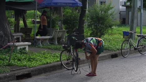 Frau-Pumpt-Einen-Fahrradreifen-Im-Lumpini-Park-In-Bangkok-Auf