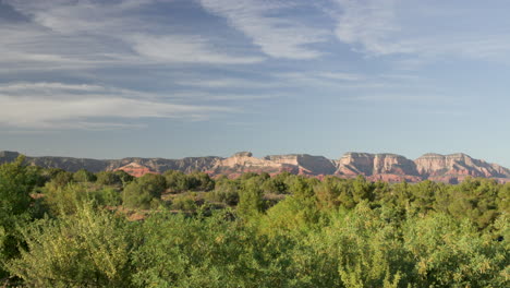 Extreme-wide-shot-of-Sedona-Red-rock-mountains-with-green-foliage-in-the-foreground