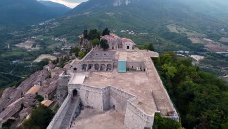 Aerial-pan-forward-shot-of-a-fort-on-top-of-a-small-town-in-Italy
