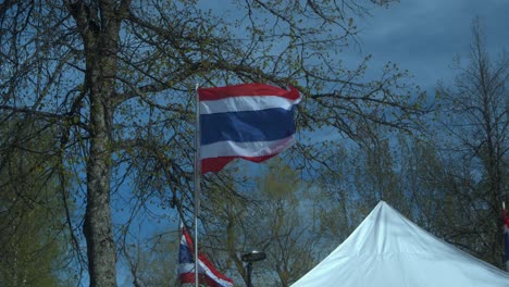 Flags-of-Thailand-fly-in-sunny-spring-breeze-at-festival-kiosk-tent