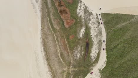 Drone-tracking-line-of-tourists-on-ATVs-on-path-through-Brazilian-sand-dunes