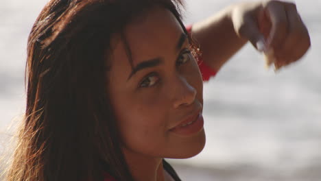Closeup-Head-shot-of-Attractive-Latin-Woman-Relaxing-on-Beach-Turns-around-to-look-back-at-Camera