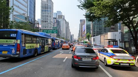 City-Buses,-Private-Cars,-And-Police-Car-Stuck-In-The-Traffic-In-The-Main-Street-Of-Gangnam-In-Seoul,-South-Korea