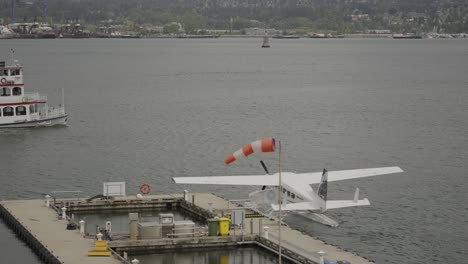 Blick-Auf-Eine-Fähre,-Die-In-Der-Bucht-Von-Vancouver-In-Der-Nähe-Des-Wasserflugzeugs-Segelt,-Das-Im-Pier-Des-Hafenflugzentrums-Angedockt-Ist,-British-Columbia,-Kanada