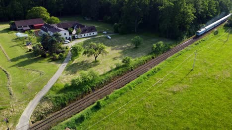 Aerial-view-of-a-diesel-train-passing-in-front-of-the-farmhouse