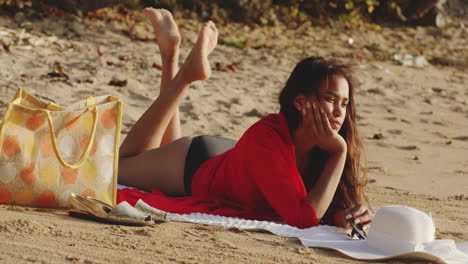 Latin-Girl-Daydreams-in-Warm-Sunlight-Lying-down-on-Tropical-Sandy-Beach,-static-shot