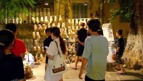 Touristische-Männer,-Frauen,-Kinder,-Die-Nachts-Auf-Alte-Artefakte-In-Der-Alten-Stadt-An-Der-Zentralen-Küste-Hoi-An-Vietnams-Blicken