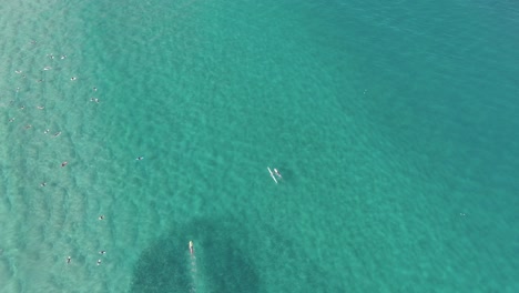 Aerial-top-view-of-surfers-floating-on-the-pristine-water-of-the-beach