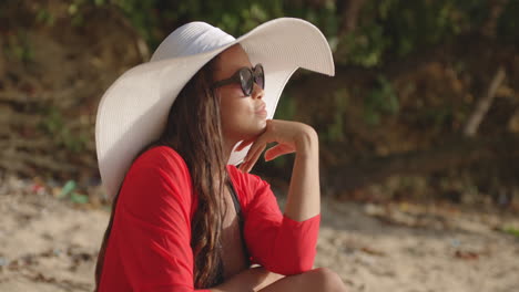 Mujer-Latina-Sueña-Despierta-En-La-Playa,-Con-Vestido-Rojo-Y-Sombrero-Blanco,-Retrato
