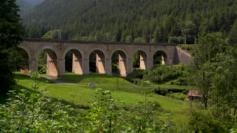Car-driving-through-beautiful-viaduct-landscape-at-Semmering-Railway-in-Austria