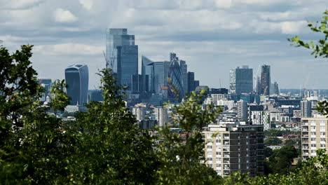 Zeitraffer-Der-Londoner-Stadtansicht-Von-Einem-Aussichtspunkt-Mit-Blick-Auf-Die-Skyline-Zwischen-Bäumen