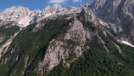 Alps-in-Albania,-green-cliff-side-on-a-mountain-peak-range-on-a-beautiful-sunny-day