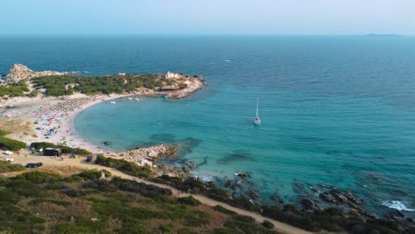 Schönes-Sardinien-Klares-Blaues-Türkis-Und-Ruhiges-Wasser-An-Einer-Natürlichen-Sandstrandküstenbucht-In-Italien-Mit-Sonne-Und-Segelschiff