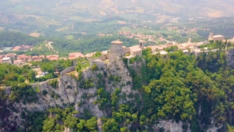 Aerial-View-Of-Guaita-Tower-On-Mount-Titano-Overlooking-The-City-In-San-Marino-Bordered-By-Italy