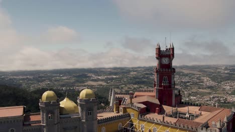 Aerial-panning-shot-around-the-clock-tower-of-Pena-palace-against-Sintra-cultural-landscape