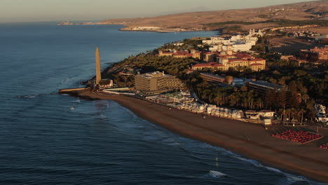 Aerial-orbit-shot-lighthouse-view-during-sunset-in-Meloneras-district-on-Gran-Canaria-island-during-magical-sunset-near-Maspalomas-dunes