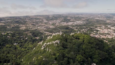 Historic-medieval-stone-ruins-of-Castle-of-the-Moors-in-Sintra-Portugal,-aerial-pan-shot