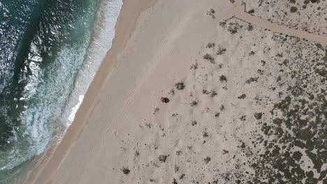 Aerial-top-down-of-one-person-lying-on-sandy-deserted-beach-in-Australia,Exmouth
