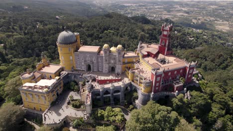 Birds-eye-view-of-popular-tourist-destination-Pena-palace-in-Sintra-Portugal,-aerial-dolly-out-shot