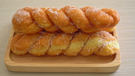 sugar-doughnut-in-spiral-shape-on-wooden-plate