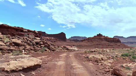 Empty-Dirt-Road-At-Desert-Of-Utah-With-Sandstone-Cliffs-At-Sunny-Day-In-United-States