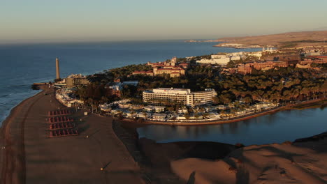Amazing-rotating-drone-view-of-a-city-by-the-sea-surrounded-by-sandy-beach-in-Gran-Canaria-island-Maspalomas-in-Spain