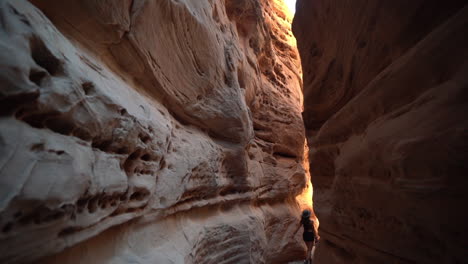 Back-of-Young-Woman-Walking-in-Unique-Narrow-Slot-Canyon-With-Red-Sandstone-Cliffs-in-Valley-of-Fire-State-Park,-Nevada-USA,-Full-Frame-Slow-Motion