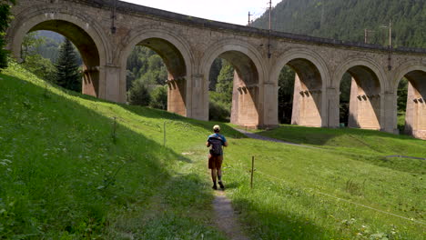 Male-hiker-walking-through-landscape-with-aqueduct-in-Semmering,-Austria