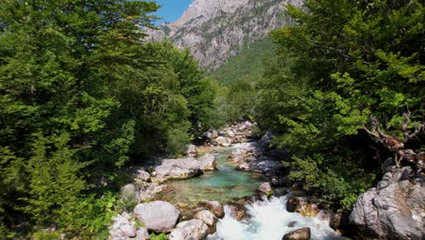 Flying-low-over-a-mountain-river-in-valley-of-Valbona,-famous-destination-for-tourists-in-Albania