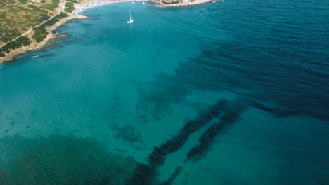 Idyllisches-Sardinien-Klares-Blaues-Türkis-Und-Ruhiges-Wasser-An-Einer-Natürlichen-Sandstrandküstenbucht-In-Italien-Mit-Sonne-Und-Einem-Segelschiff