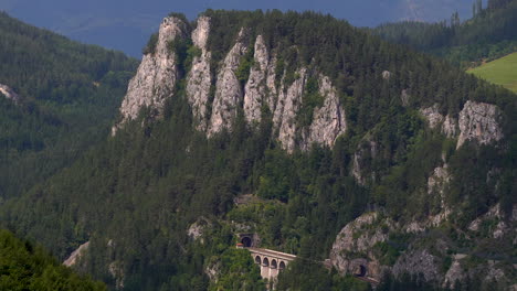 Slow-tilt-up-over-rocky-cliffs-with-train-tracks-in-stunning-nature-landscape