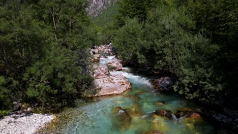Clean-emerald-water-of-Valbona-river-in-Albania,-streaming-and-foaming-through-cliffs-and-green-trees