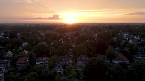 Low-aerial-of-houses-in-a-suburban-neighborhood-at-sunrise---drone-flying-backwards