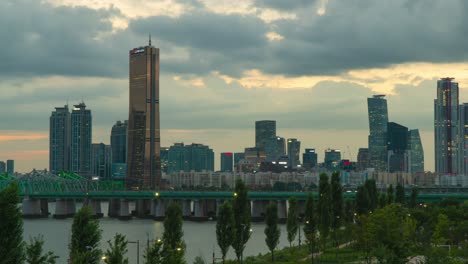 63-SQUARE-Building-Skyscraper-Sunset-Skyline-and-Railway-bridge-subway-train-fast-passing-Han-river-In-Seoul,-South-Korea