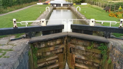 a-slow-rising-reveal-shot-of-a-very-large-and-old-wooden-locks-on-a-very-cloudy-and-overcast-day-in-a-famous-lock-in-england-called-the-kennet-and-avon-canal