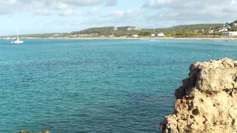 Wide-Distant-view-of-Son-Bou-beach-the-longest-in-Menorca,-clear-and-calm-water-with-boats,-Balearic-Islands,-Spain