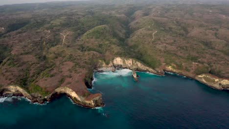 Aerial-view-of-turquoise-ocean-waves-crashing-coastline-of-the-Broken-Beach-famous-tourist-place-on-the-Nusa-Penida-island,-Indonesia
