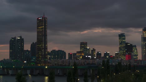 Rascacielos-De-63-Cuadrados-En-La-Isla-De-Yeouido-Con-El-Puente-Ferroviario-Hangang-En-Primer-Plano-Por-La-Noche-En-Seúl,-Corea-Del-Sur