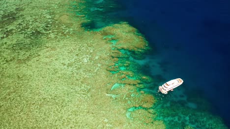 Solitary-Yacht-Docked-In-View-Of-The-Great-Barrier-Reef--aerial-shot