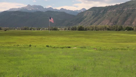 Large-American-Flag-waving-in-the-wind-over-a-meadow-with-the-San-Juan-Mountains-in-background