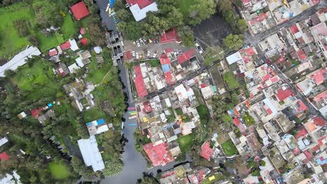 Slowly-jib-down-above-houses,-chinampas-and-canal-in-Xochimilco,-Mexico-City