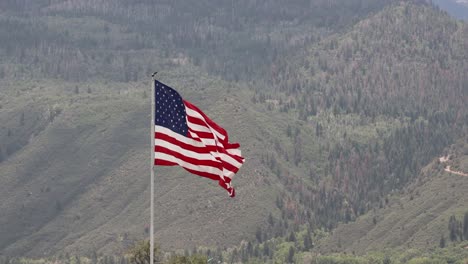 Gran-Bandera-Americana-Ondeando-En-El-Viento-Las-Montañas-De-San-Juan-En-Segundo-Plano.