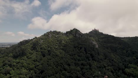 Aerial-ascending-shot-capturing-beautiful-cloudscape-and-Pena-palace-in-far-distance-mountain