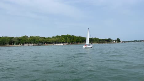 Long-Shot-of-Monohull-Sailboat-Sailing-Around-Beautiful-Island-in-Venice,-Italy