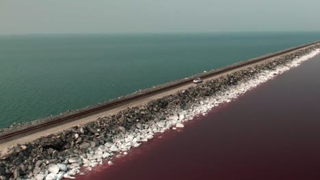 TRUCK-CROSSING-THE-ROAD-OVER-THE-PINK-AND-BLUE-WATER-LAKE-IN-THE-GREAT-SALT-LAKE