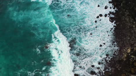 Aerial-shot-of-turquoise-ocean-waves-crashing-black-sand-coastline-of-Nusa-penida-island,-one-of-the-tourist-attractions-of-Bali-island-Crystal-beach-kelingking-beach-angle-billabong-broken-beach