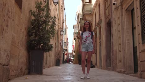 Young-Woman-Standing-In-The-Street-While-Looking-At-Historic-BuildingIn-Valletta,-Malta